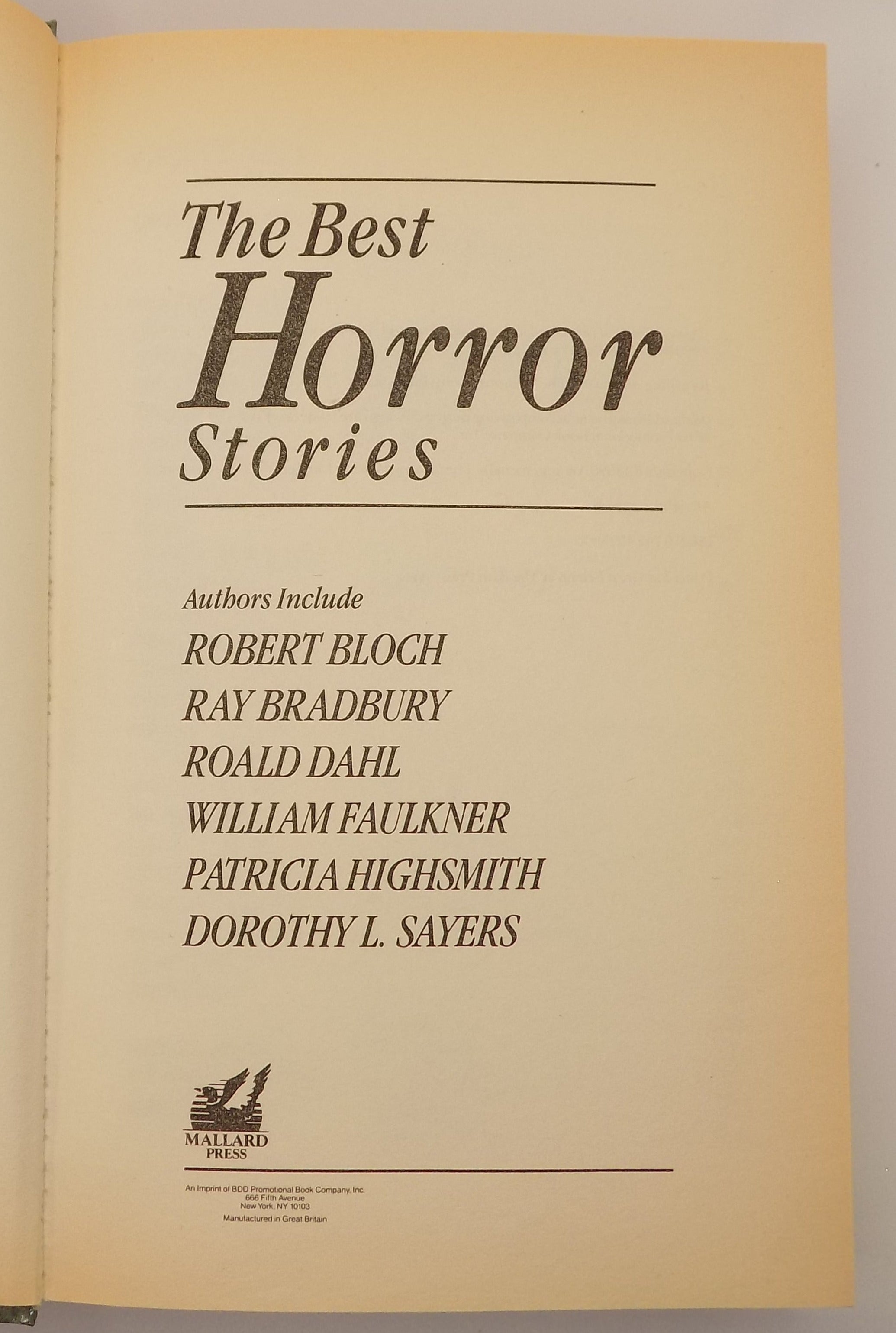 Open book titled 'The Best Horror Stories' held by a hand against a neutral background